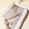 A close-up view of a beige baby winter snow boot with a fluffy lining and white sole.