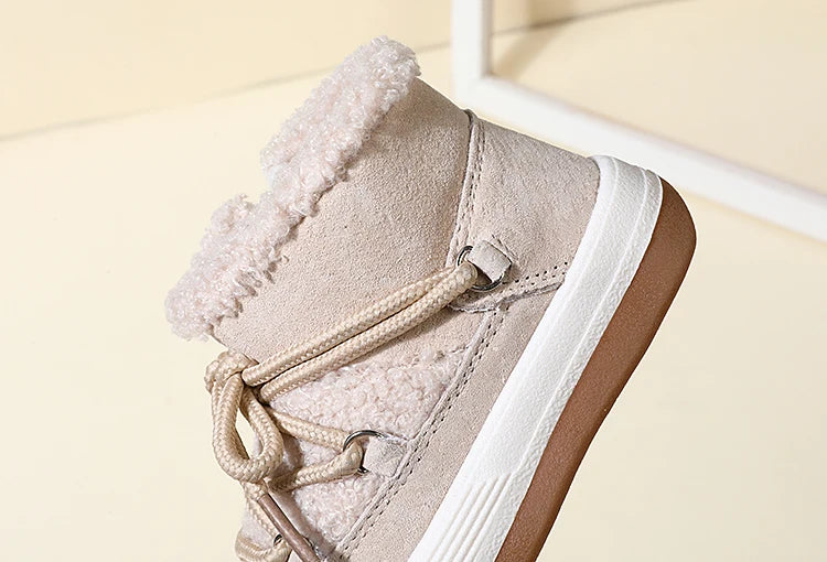 A close-up view of a beige baby winter snow boot with a fluffy lining and white sole.