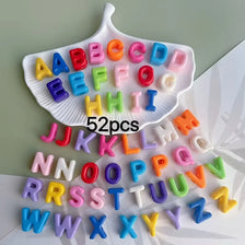 A white tray holds 52 alphabet letter beads in various colors for jewelry and crafting.