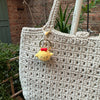 A handcrafted crochet animal keychain featuring a yellow rabbit or chick charm hanging from a gold-toned metal loop.