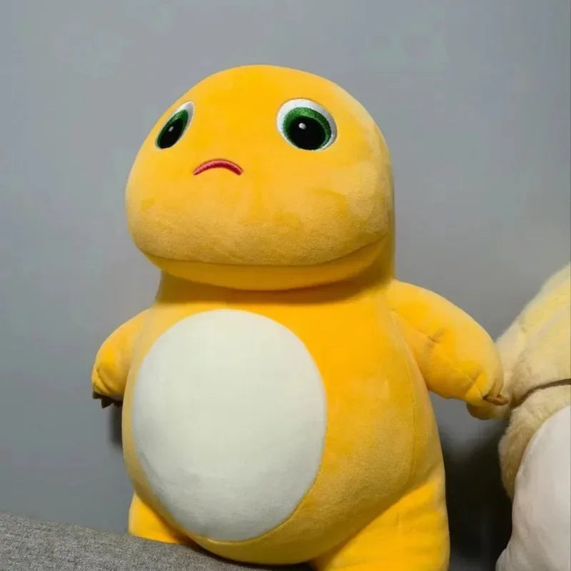 A yellow dinosaur plush toy with large green eyes and a white belly is shown against a gray background.