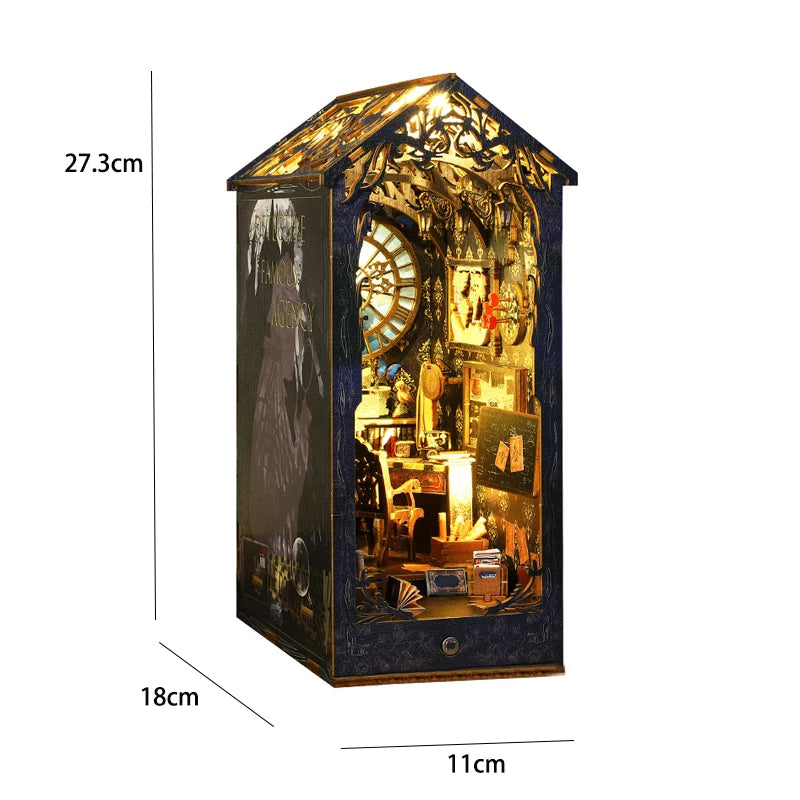 A dark blue miniature bookshelf book nook kit featuring a detailed diorama with illuminated elements and a tree canopy.