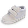 A pair of light gray canvas baby sneakers with white accents and a soft, padded design.