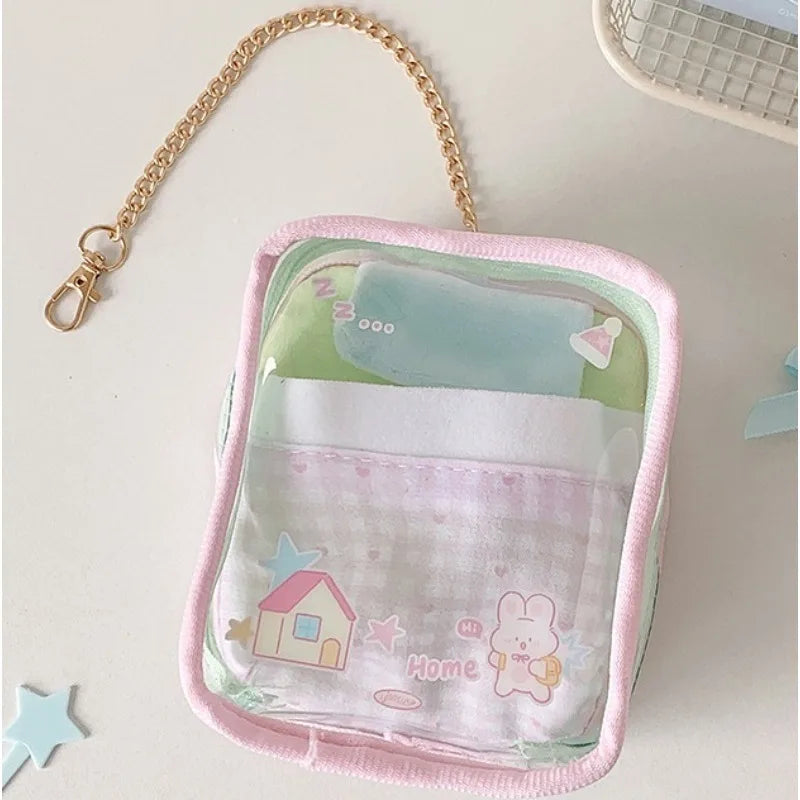 Pink storage pouch with a clear window and a decorative keychain attached to a gold chain.