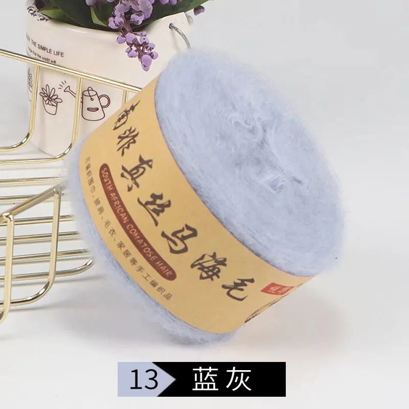 A ball of light blue mohair blended yarn for knitting shawls and sweaters is displayed next to a gold wire rack.