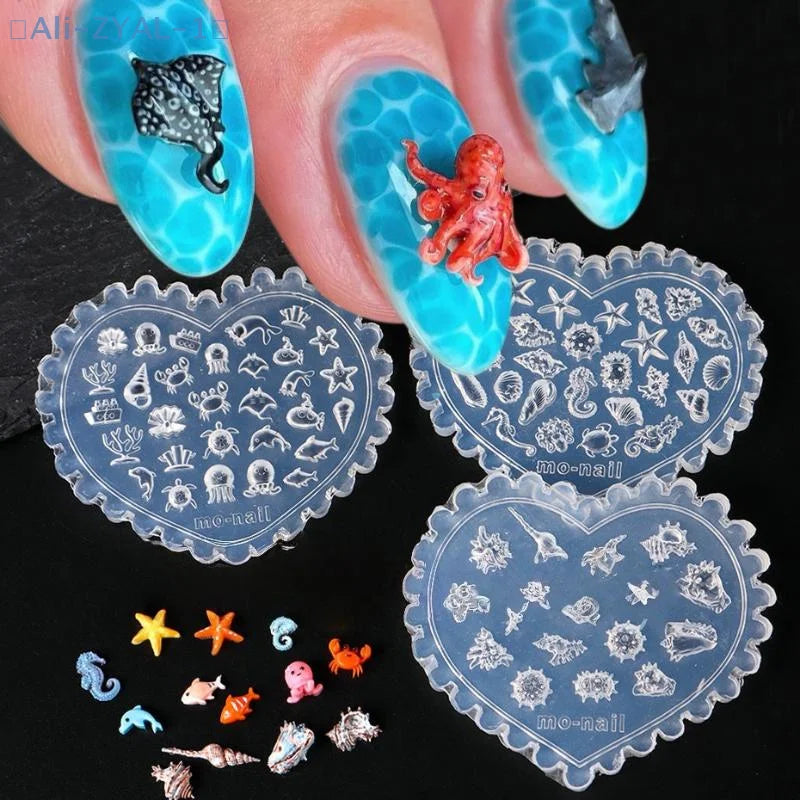 A hand holds a clear blue silicone nail art mold featuring sea shell, starfish, and ocean designs.