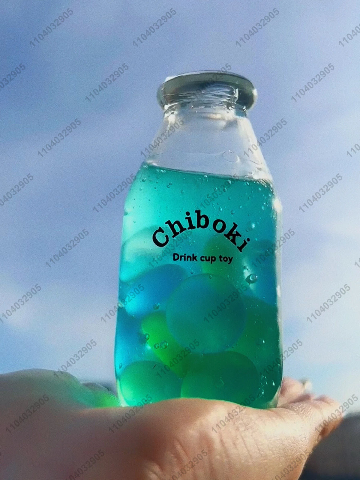 A clear bottle filled with green liquid, labeled Chiboki, resting in an open hand.