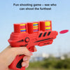 A hand holds a red soft foam flying disc launcher toy, aiming it outdoors.