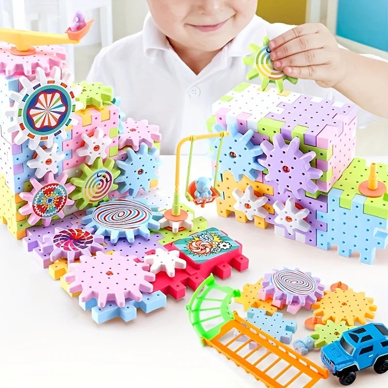 A child is assembling a colorful set of motorized gear building blocks and a rail car on a white table.