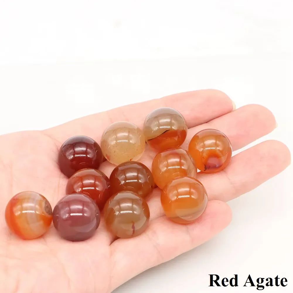 A hand holds a cluster of polished Red Agate crystal spheres.