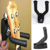 A black guitar wall mount hanger with soft padding is shown attached to a wooden guitar neck.