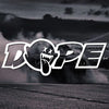 A black car is performing a burnout, with the DOPE decal logo visible in the foreground against a dark, moody background.