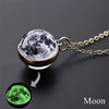 A pendant necklace featuring a glass sphere depicting the moon, with an inset showing a glow-in-the-dark green moon.