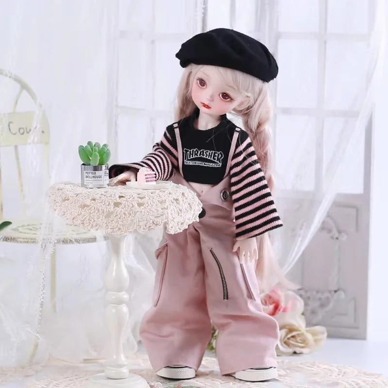 A light pink princess doll wearing a black beret and a striped shirt with overalls.