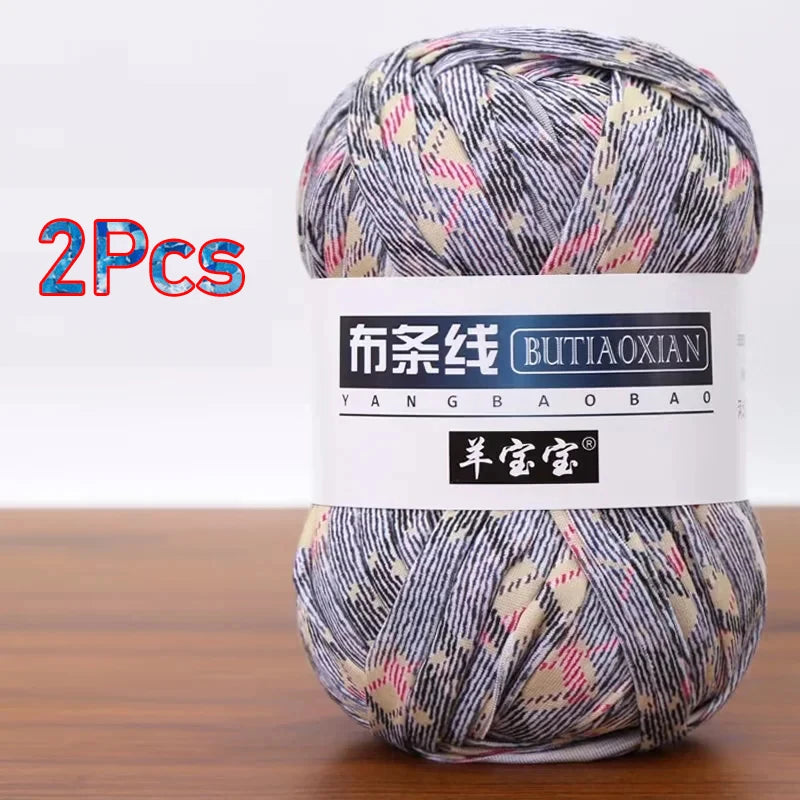 A ball of soft chunky t-shirt yarn in a patterned mix of gray, white, and pink is shown.