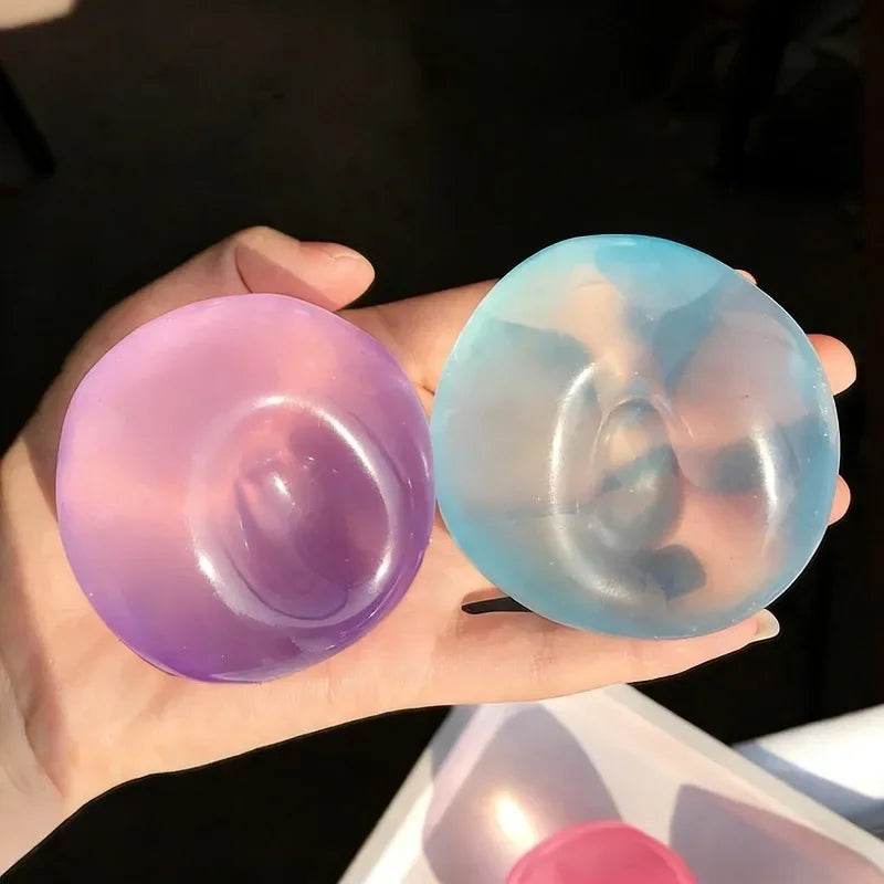 A hand holds two translucent squishy stress balls, one purple and one blue-green.