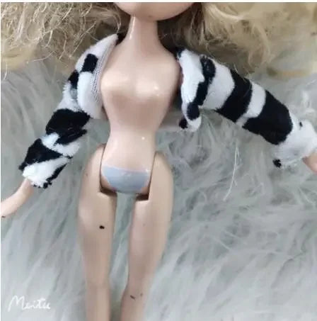 A fashion doll with long blonde hair wearing a black and white striped fur outfit.