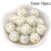 A bowl filled with ten white silicone beads decorated with yellow and blue floral patterns for DIY jewelry making