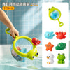 A hand is holding a yellow water squirting turtle bath toy with a fishing net, surrounded by various colorful bath toys.