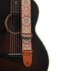 An embroidered guitar strap featuring intricate patterns in orange, blue, and white thread with leather ends.
