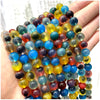 A hand holds a string of natural stone beads including amethyst, garnet, and labradorite in various colors.