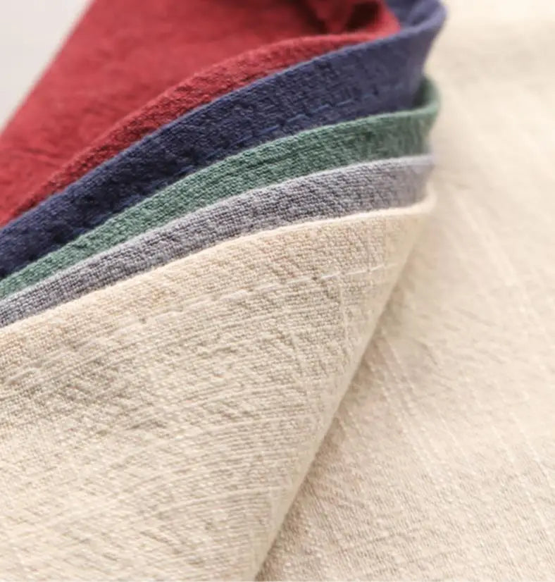 A stack of folded classic cotton-linen dinner napkins in various shades of red, blue, green, and gray.