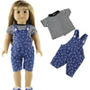 A doll wearing a navy blue patterned outfit set consisting of overalls and a striped shirt.