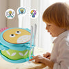A young child is playing with a blue and green owl double-sided musical drum for kids.