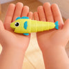 A yellow and blue plastic fish toy is held in a child's hand.