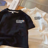 A black crew neck t-shirt with the text LET'S BUILD TOYCARWORLD TOGETHER on the chest, next to a white t-shirt with similar t