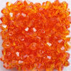 A pile of faceted orange glass bicone beads for jewelry making.