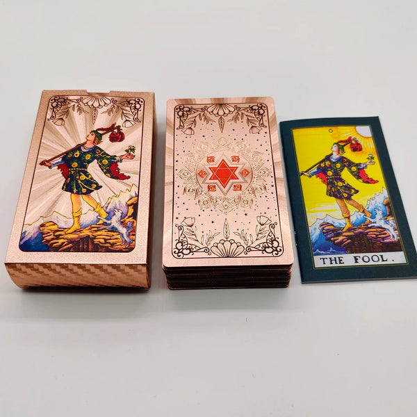 A set of gold foil tarot cards and guidebook featuring an illustration of a figure in historical attire.