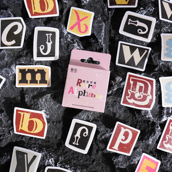 A collection of vintage letter stickers in various colors and styles scattered on a dark, textured surface.
