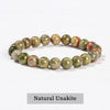 A bracelet made of natural unakite stones in shades of green and pink.