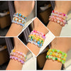 A collection of colorful frosted golden foil acrylic beads arranged in various bracelets on a person's wrist.