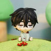 A black-haired anime figure with red eyes sits on green terrain.