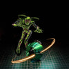 A green, insect-like figure is positioned above a glowing orange ring around a metallic sphere on a grid surface.