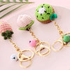 Handmade crochet fruit keychain pendants in pink and green colors displayed on a light pink plate.