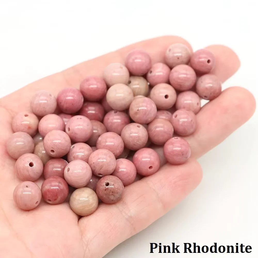 A hand holds pink rhodonite round beads for jewelry making