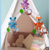 Cute stylized multi-scene hanging toys for infants, including a blue cat and an orange bear, displayed in a fabric crib.