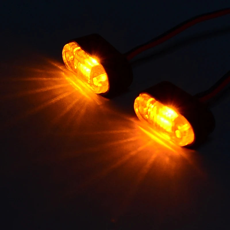 A pair of bright orange LED warning lights shining beams onto a dark surface.