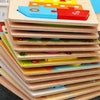 A stack of colorful wooden shape puzzles for kids featuring various geometric and organic shapes.