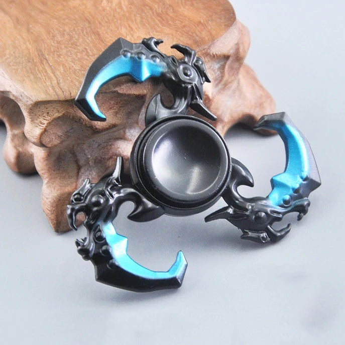 A metal fidget spinner with a rainbow finish rests on a piece of wood.