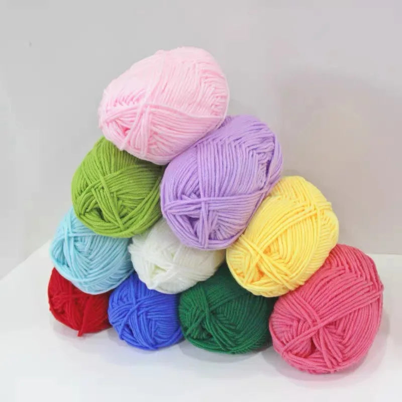 A collection of pink, purple, green, and yellow pre-dyed milk cotton yarn balls arranged on a white surface.