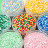 A collection of colorful pony beads in various shades including pink, green, yellow, and blue, displayed in clear jars.