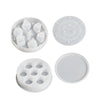 A set of white silicone resin molds including a bowl, a flat disc, and a round tray for custom dice boxes.