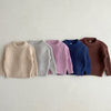 A row of nine pastel colored knit baby pullover sweaters for boys and girls displayed against a light background.