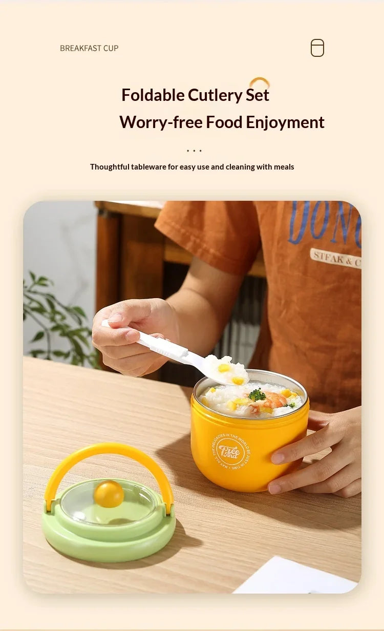 A hand is holding a yellow insulated stainless steel breakfast cup with a lid on a wooden table.