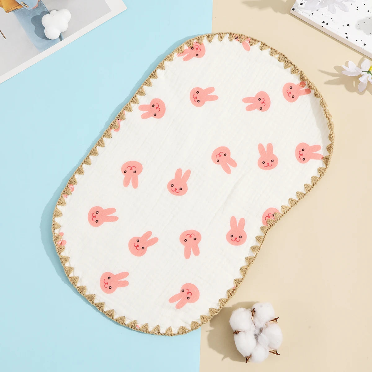 A white embroidered flat pillow with pink bunny designs on a light blue background.