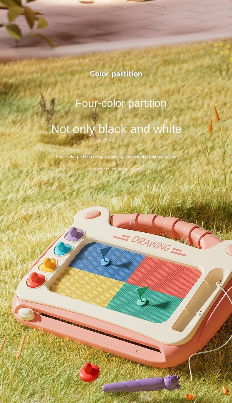 A pink magnetic drawing board with colorful shapes and a purple pencil lying on green grass.